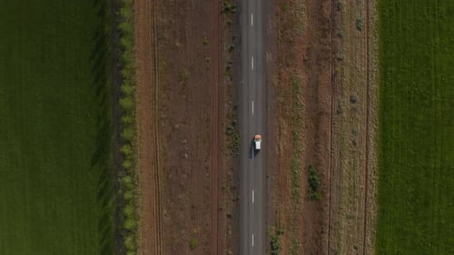 Vue aérienne aérienne de haut en bas d'une voiture circulant sur une route droite entourée de bandes de sable