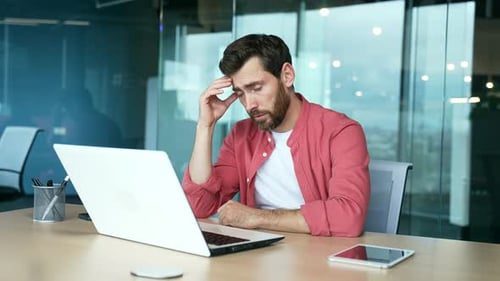 Homme d'affaires mûr et stressé, inquiet, au bureau d'un centre d'affaires moderne, se sentant mal à propos de ses finances