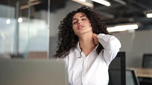 Businesswoman Massages Neck Due to Computer Work Stress in Office