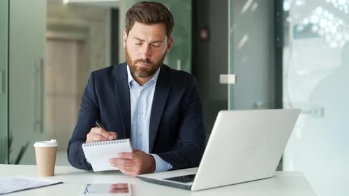 Man working in office writing notes