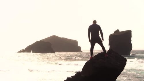 Man silhouette standing on rock against monsteiros beach in Sao Miguel, Azores Island.