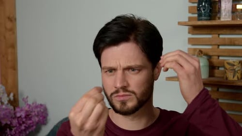 Bearded Man Gesturing and Styling Dark Hair Indoors