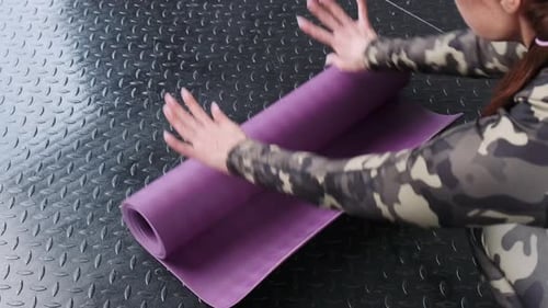 Woman Unfurling Purple Yoga Mat on Black Floor