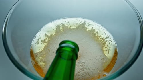 Bottle Pouring Craft Beer in Transparent Glass Closeup. Lager Stream Making Foam