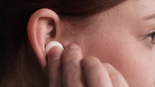 Woman Inserts Wireless Earbud in Ear Close Up