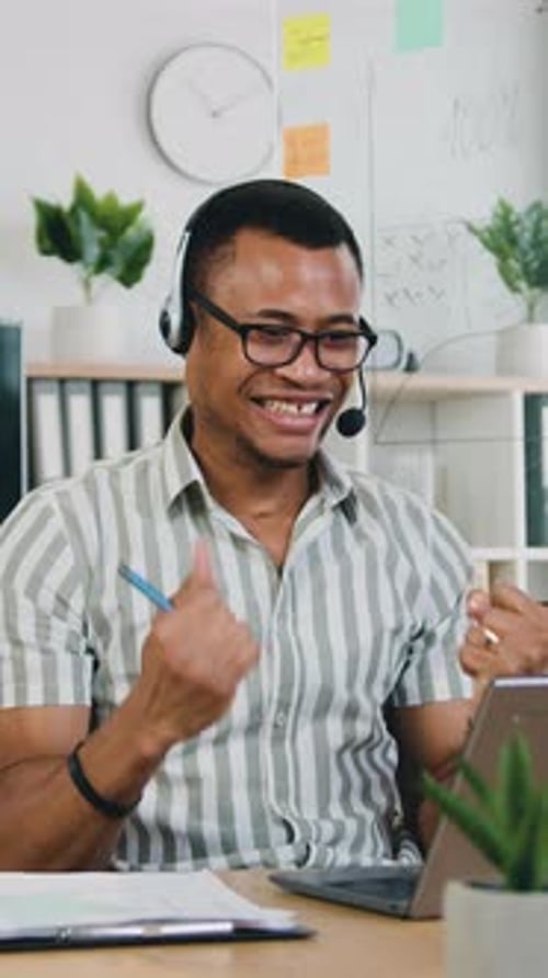 African American Office Manager in Wireless Headphones Sitting at Workplace and Typing on Keyboard