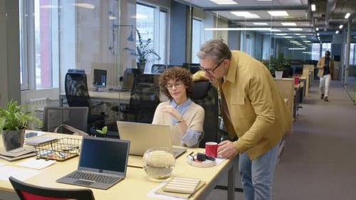 Coworkers Talking at Desk in Modern Office