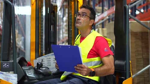 Travailleur masculin heureux conduisant un chariot élévateur à un entrepôt de distribution
