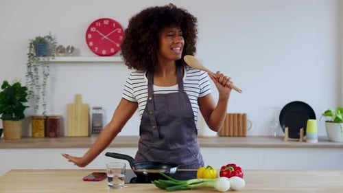 Happy Woman Sings While Cooking in Kitchen