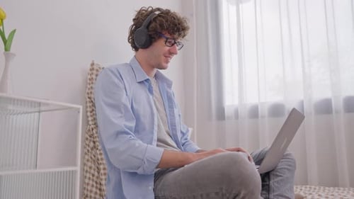 Young Adult Celebrating Success with Laptop at Home