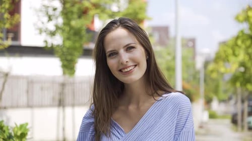 A Beautiful Young Caucasian Woman Smiles at the Camera in a Street in an Urban Area