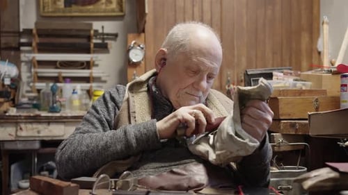 Senior Gray Haired Male Master in a Wheelchair Working at His Workshop Sharpening Japanese Swords