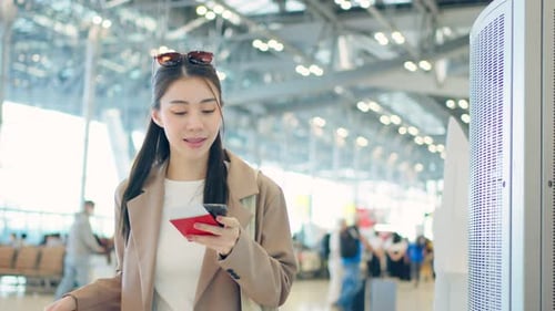 Asian young woman passenger checking depature boarding pass in airport.
