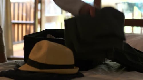 Man packing hat and clothes, in his bag and leaving the hotel room, in Thailand - Slider shot