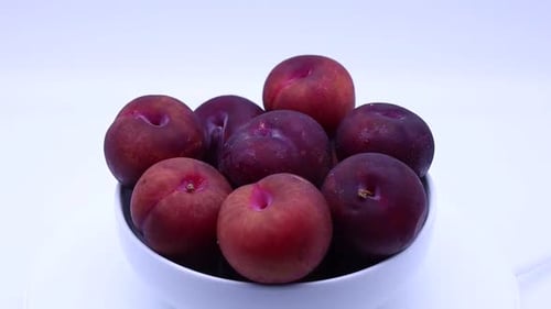 Fresh plums in a bowl isolated on white background