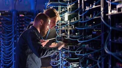 Two men analysing servers in a data centre in slow motion