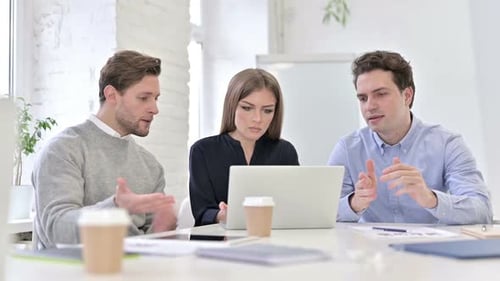 Frustrated Colleagues Looking at Laptop in Office
