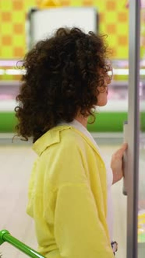 Woman Choosing Salami in Refrigerated Section at Supermarket
