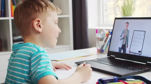 Junge macht seine Hausaufgaben am Tisch Süßes Kind lernt zu Hause mit Hilfe des Laptops