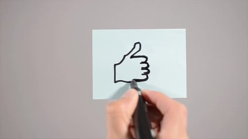 Hand Draws Thumbs Up Symbol on Sticky Note
