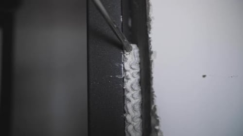 Spray Gun Fills Up a Gap Between the Wall and a Door with Construction Sealant