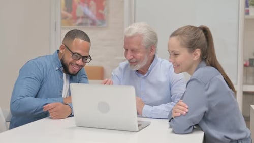 Colleagues Work Together at a Laptop in the Office