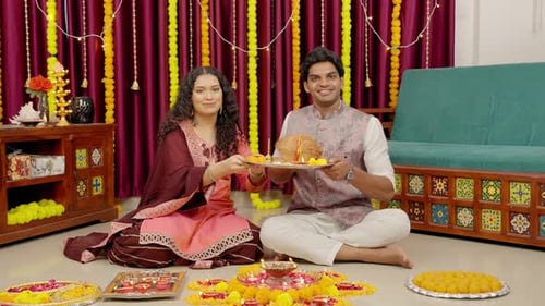 Couple Holding Diwali Sweets at Home