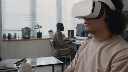 Young Developer in Headset Testing VR Application Using Laptop at Workplace