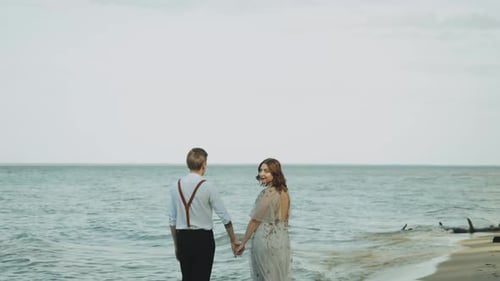 Beautiful Young Couple in Love Walking Along the Beach While the Waves Flood the Beach Enjoying the