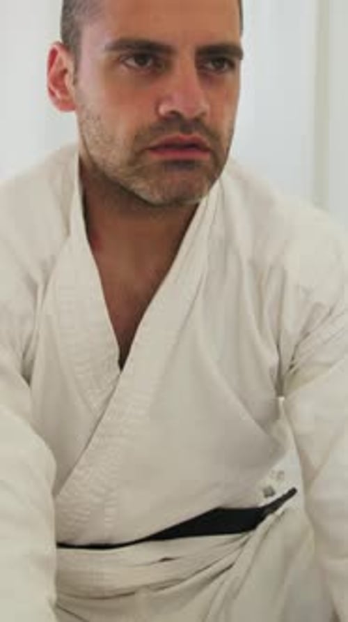 Man in Karate Gi Sitting on Floor Stretching