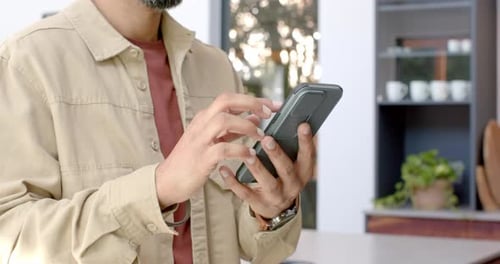 Nachricht eingeben, Mann benutzt Smartphone in moderner häuslicher Umgebung