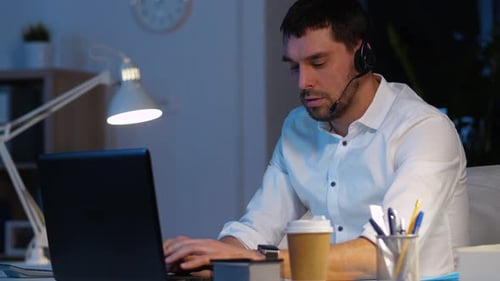 Man with Headset Working Late on Laptop