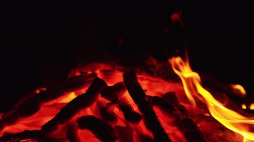 Glowing Flames Engulfing Wood in a Dark Setting
