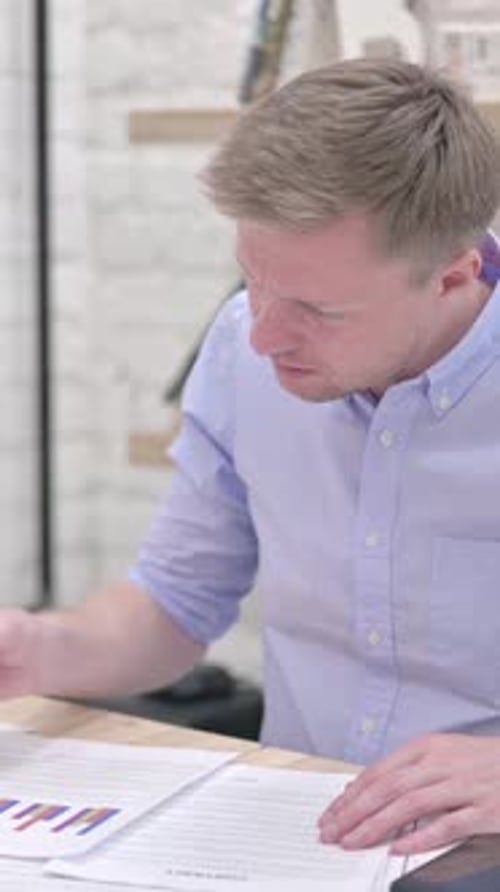 Focused Man Analyzing Charts and Contract at Desk