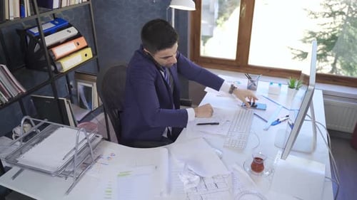 Busy businessman talking on the phone and working looking at papers.