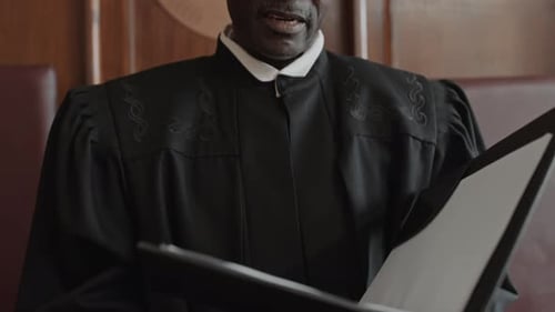 Mature Male Judge Reading out Decision of Court during Hearing