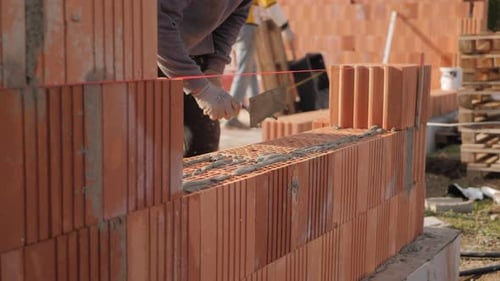 Construction Worker Laying Bricks with Mortar