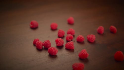 Red Raspberries Scattered on Dark Brown Table