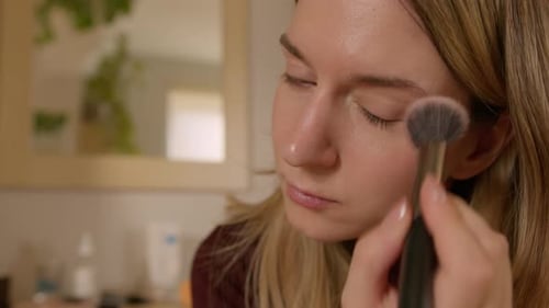 Woman Applying Makeup with Brush in Close-Up