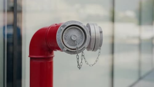 Nahaufnahme eines roten Hydranten mit Staubkappe und Kette in urbaner Umgebung