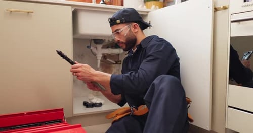 Plumber Repairing Sink in a Kitchen