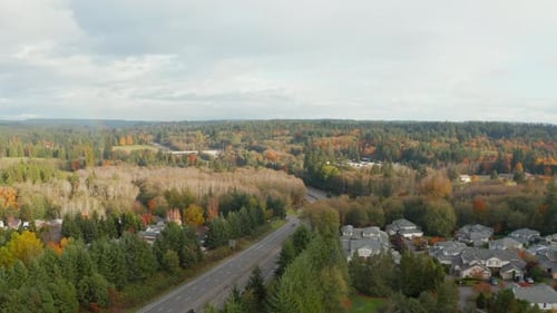 Aerial view of multi lane highway traffic through forest with scattered residential houses in Washin