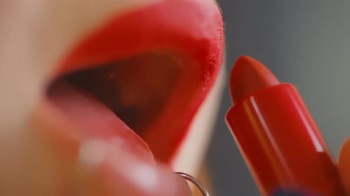 Woman Applying Vibrant Red Lipstick in Macro Detail