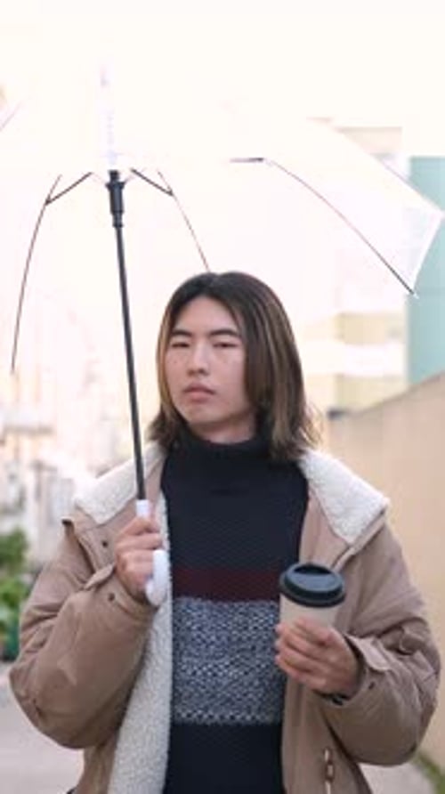 Young Adult Walking with Coffee and Umbrella
