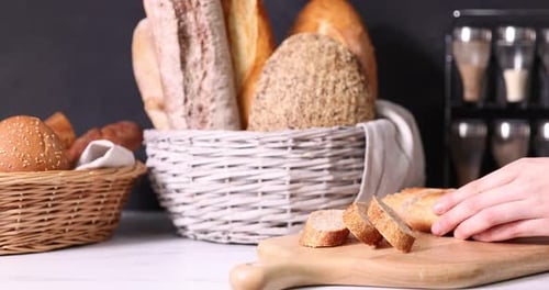 Frau schneidet frisch gebackenes Brot an weißer Arbeitsplatte, Nahaufnahme