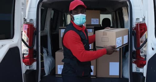 Afrikanischer Kurier liefert Pakete mit einem LKW mit Gesichtsmaske in Südafrika