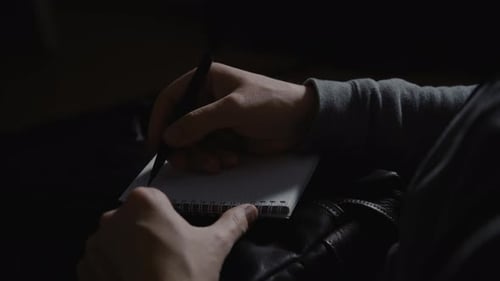 a man is writing notes on white paper.