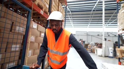 Warehouse Worker Pushing Cart Through Aisles