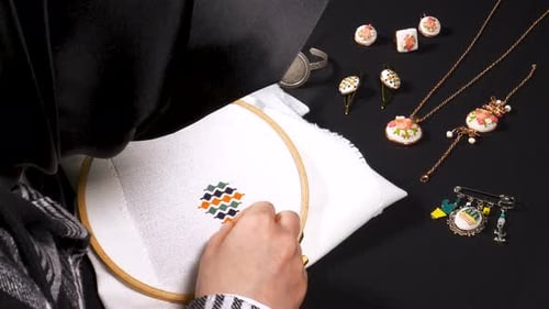 Woman Creating Embroidery Pattern, Floral Jewelry Displayed