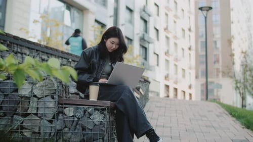 Woman Works on Laptop on Urban Bench